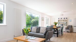 Ein modernes Wohnzimmer mit Sofa, Couchtisch und Essbereich mit Stühlen und Tisch.