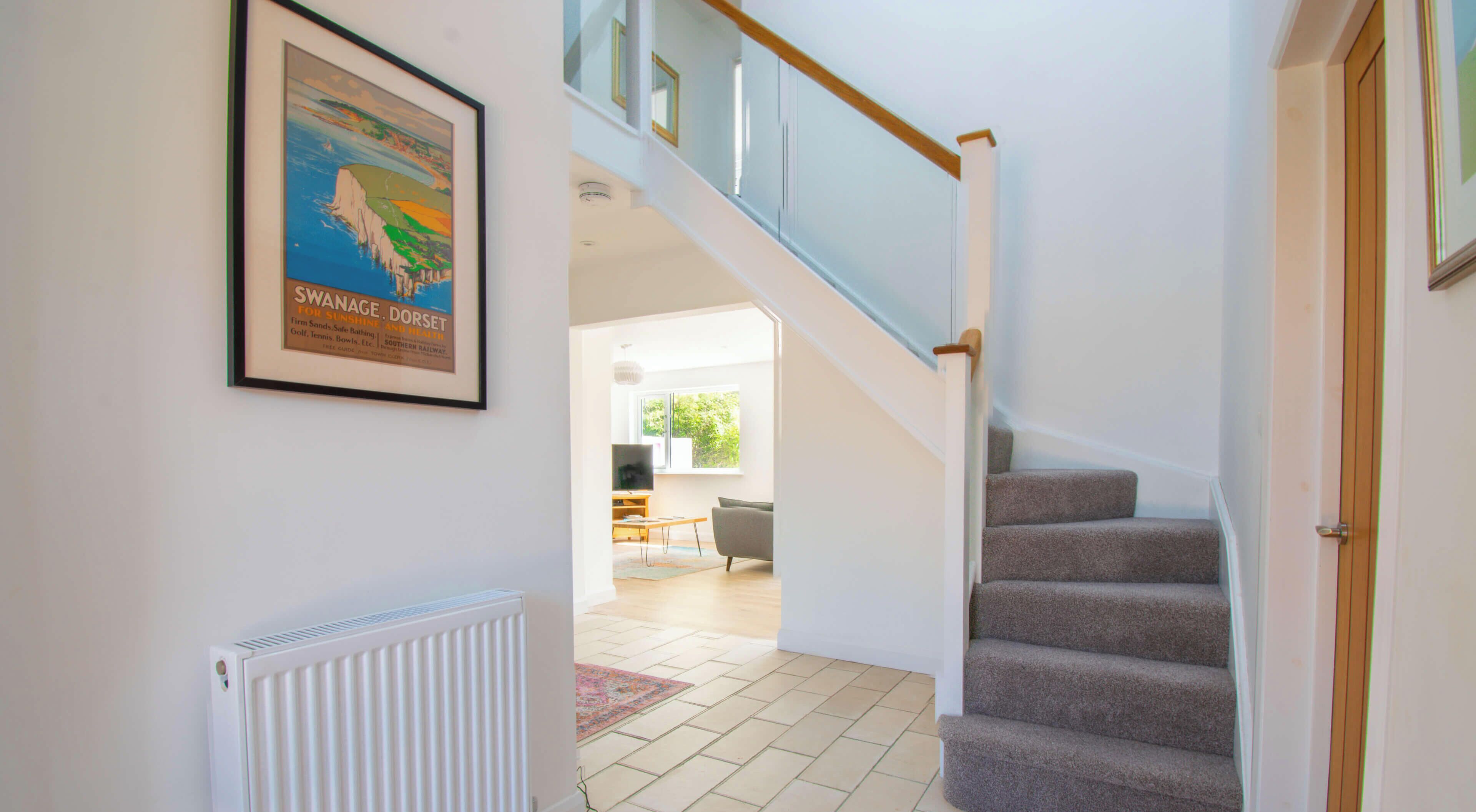 Un escalier menant à un espace de vie, avec une affiche encadrée accrochée au mur.