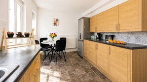 Een moderne keuken met houten kastjes, een zwart aanrecht en een eethoek met een tafel en stoelen.