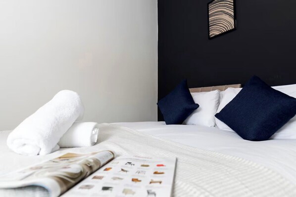 A neatly made bed with white linens, a rolled white towel, and a magazine on the bed. - 3BR Home in Darlington | Contractor Rates (Darlington)