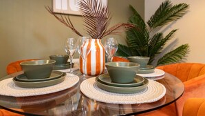 A dining table with green plates and bowls, a striped vase, and a potted plant in the background. - Darlington 3BR – Bright, Spacious & Stylish (Darlington)