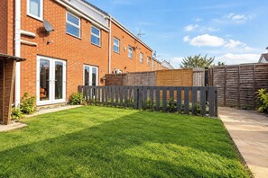 A residential property with a well-maintained lawn, a wooden fence, and a brick house with multiple windows. - Darlington 3BR – Bright, Spacious & Stylish (Darlington)