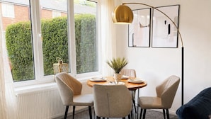 A dining area with a round table, four chairs, a potted plant, and framed artwork on the wall. - Modern 3BR | Close to Durham Centre (Belmont)