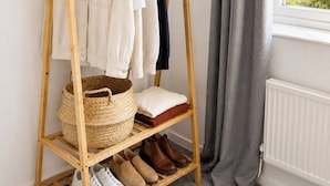 A wooden clothing rack with hangers, a woven basket, and shelves with shoes. - Modern 3BR | Close to Durham Centre (Belmont)