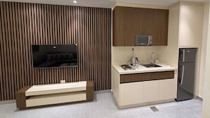 A modern kitchen with a built-in microwave, a refrigerator, a sink, and a bench. - 106 JRE One-br Apartment in Amman (Amman)
