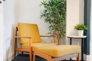 A corner room with a wooden chair, a small table, and a potted plant. - Modern and Fancy 2BR Durham | Contractor Rates (Sherburn Hill)