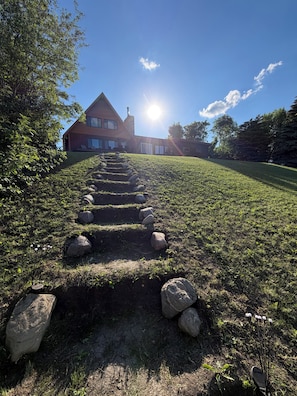 A pathway leading to a house with a stone staircase and a clear sky.