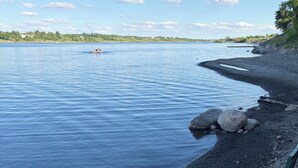 Blick auf einen See mit Stühlen und einer felsigen Uferlinie.