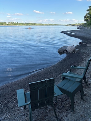 A lakeside view with chairs and a rocky shoreline.