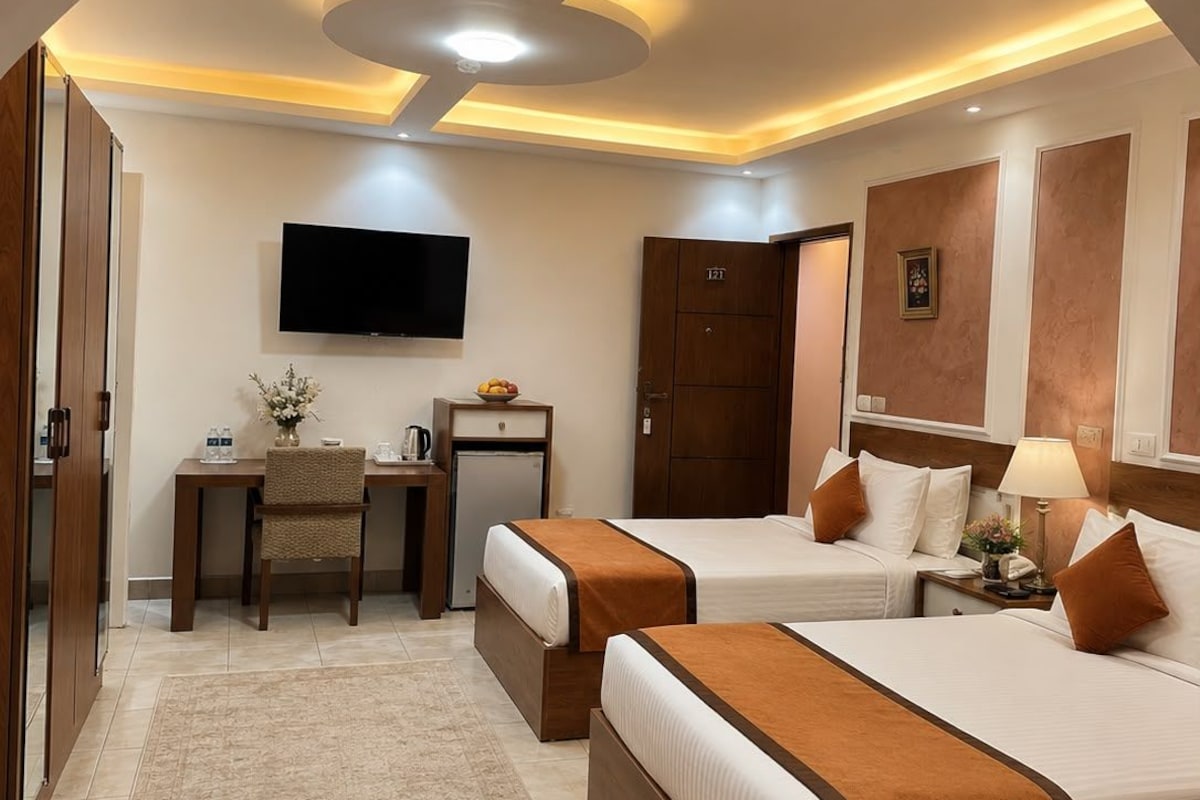 Una habitación de hotel con dos camas, un escritorio, un televisor y una puerta con un número.