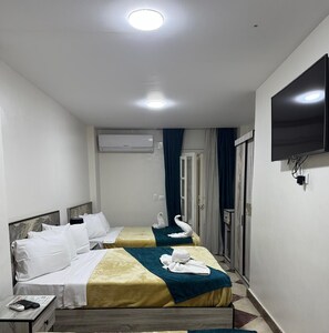 A hotel room with two beds, a TV, an air conditioning unit, and a door leading to a bathroom.