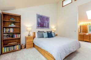 Un dormitorio con una cama grande, una estantería, un cuadro y un tocador con luces.