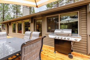 Un patio al aire libre con una parrilla, una mesa y sillas.