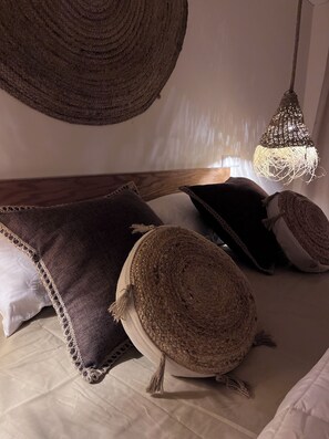 Ein gemütliches Zimmer mit einem Bett, einer gewebten Pendelleuchte und einem strukturierten Wandbehang.