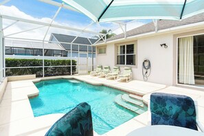 Ein Poolbereich mit Glasveranda, Liegestühlen und einem Tisch.