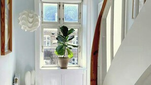 Eine Treppe mit einer Holzhandlauf, einem weißen Heizkörper, einer Blumentopf-Pflanze und einem weißen Hasen-Objekt.