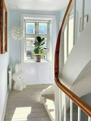 Eine Treppe mit einer Holzhandlauf, einem weißen Heizkörper, einer Blumentopf-Pflanze und einem weißen Hasen-Objekt.