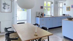 Eine Küche mit Esstisch, Stühlen, einer Pendelleuchte und einem Fenster.