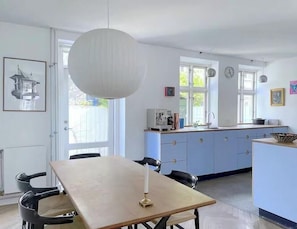 Eine Küche mit Esstisch, Stühlen, einer Pendelleuchte und einem Fenster.