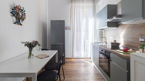Cozinha moderna com área de jantar, geladeira e janela com cortinas leves.