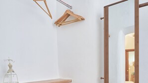 Une pièce avec un banc en bois, un miroir et un porte-manteau en bois fixé au mur.