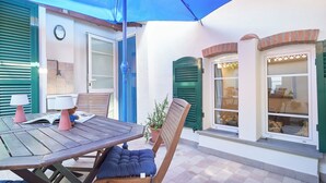 Un espace patio aménagé avec une table, des chaises, un parasol bleu et une plante en pot.