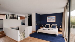 Een slaapkamer met een bed, een trap en een uitzicht door een groot raam.