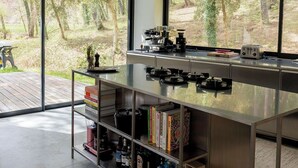Een moderne keuken met een groot eiland, inbouwplanken en uitzicht op een bebost gebied.