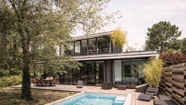 Een modern huis met twee verdiepingen, een zwembad, buiten zitplaatsen en een houten terras.