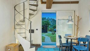 Una escalera de caracol conduce a una puerta con vistas a un jardín y montañas.
