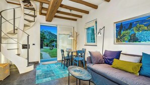 Un interior moderno con una escalera de caracol, un comedor, un sofá con cojines y un cuadro en la pared.