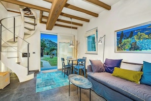 Ein modernes Interieur mit einer Wendeltreppe, einem Essbereich, einer Couch mit Kissen und einem Gemälde an der Wand.