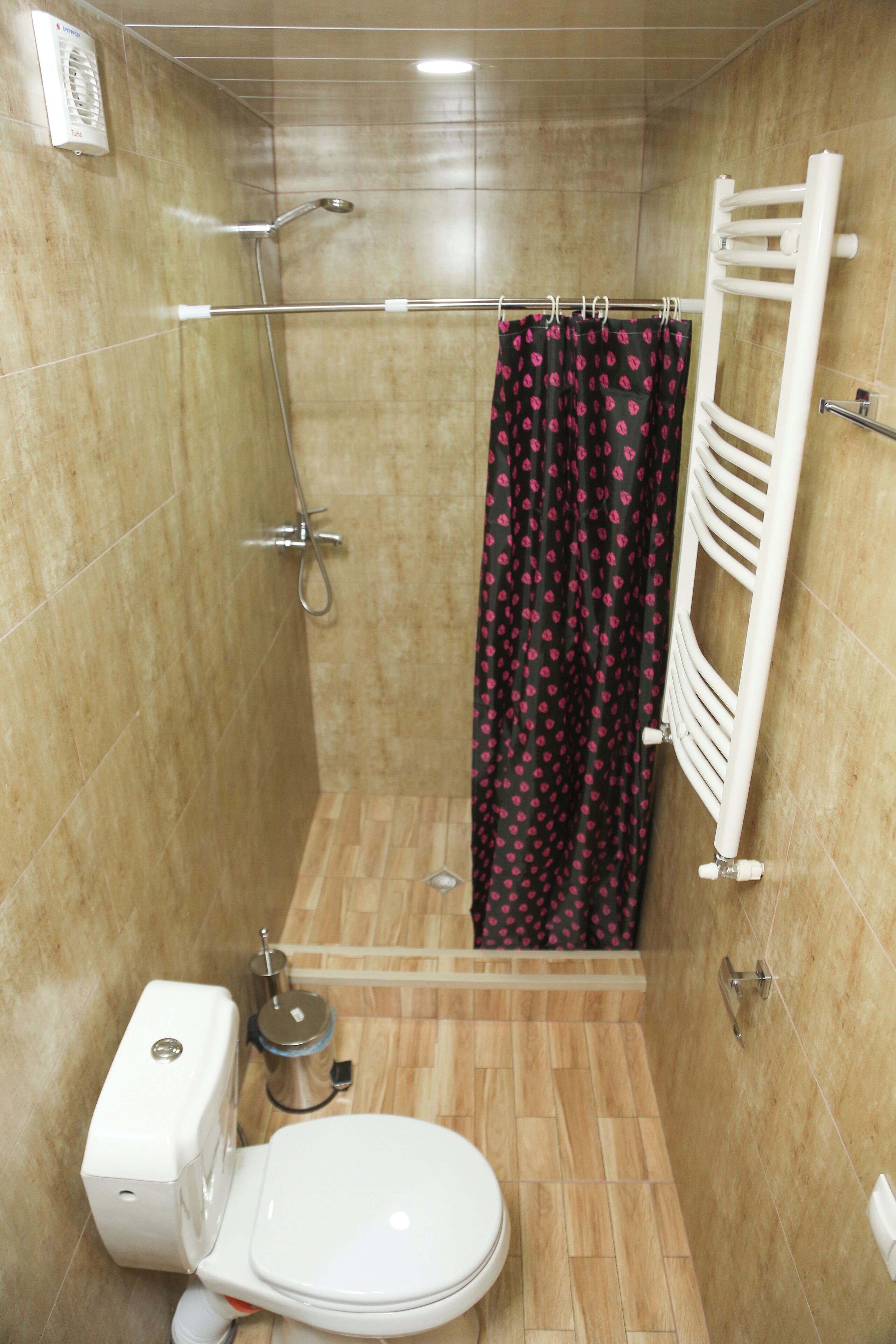 A small bathroom with a shower, toilet, and a towel rack.