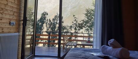 A wooden interior with a bed, a radiator, and a sliding glass door leading to an outdoor deck.