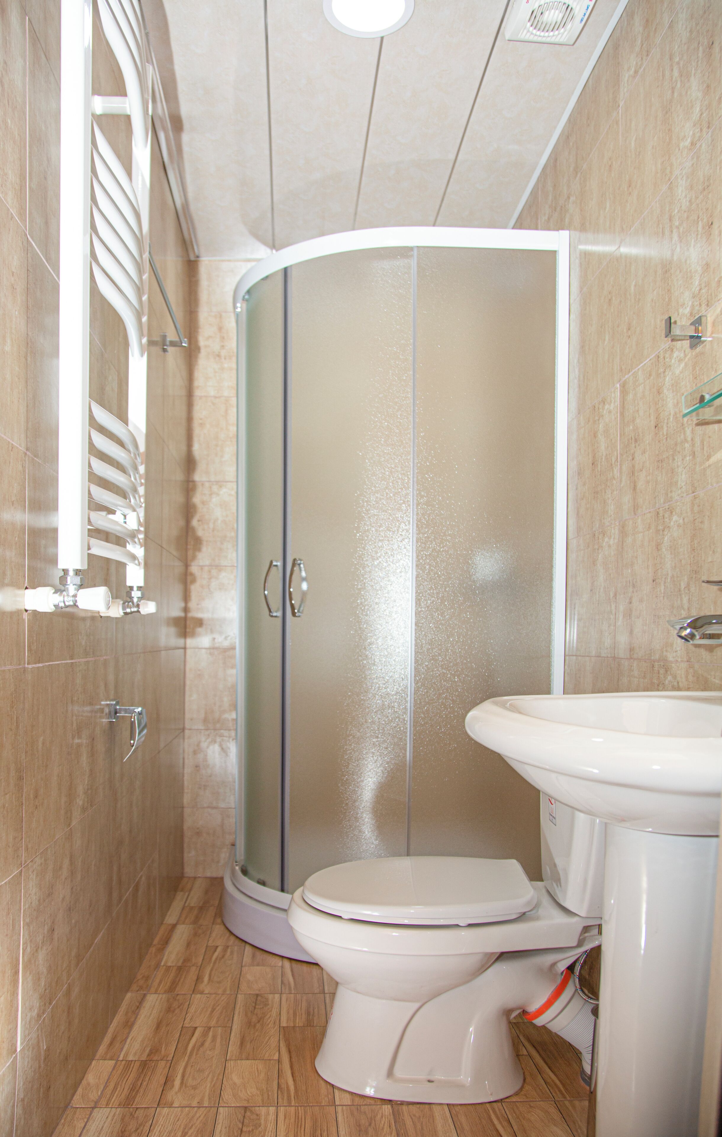 A bathroom with a shower enclosure, toilet, and sink.