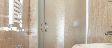 A bathroom with a shower enclosure, toilet, and sink.