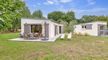 Una casa moderna con un patio, mobiliario exterior y un jardín pequeño.