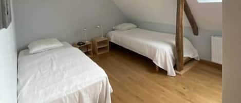 Un dormitorio acogedor en el ático, con dos camas, vigas de madera y un tragaluz.
