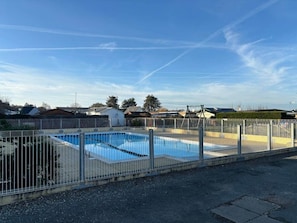 A rectangular swimming pool surrounded by a metal fence, with a clear blue sky above. - Mobilhome in Residential leisure park (Hauteville-sur-Mer)