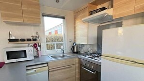 Ett kompakt kök med mikrovågsugn, spis, diskho och träskåp.