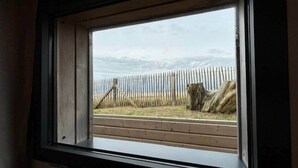 Finestra amb vista a una tanca de fusta i un tronc d'arbre a l'exterior.