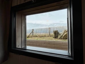A window with a view of a wooden fence and a tree stump outside. - La Perle des Dunes-Seafront-Direct beach access (Montmartin-sur-Mer)