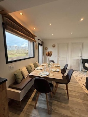 A dining area with a long table, chairs, a bench, and a window with a view. - La Perle des Dunes-Seafront-Direct beach access (Montmartin-sur-Mer)