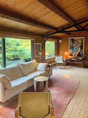 A wooden interior with a sofa, chairs, a small table, and a painting. - Authentic 70s summer house by Skærby Strand (Nykøbing Sj)