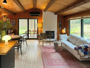 A cozy living room with a fireplace, wooden ceiling, and large windows. - Authentic 70s summer house by Skærby Strand (Nykøbing Sj)
