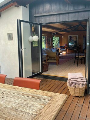 An open door leading to a room with a sofa, a chair, a table, and a basket of cushions. - Authentic 70s summer house by Skærby Strand (Nykøbing Sj)