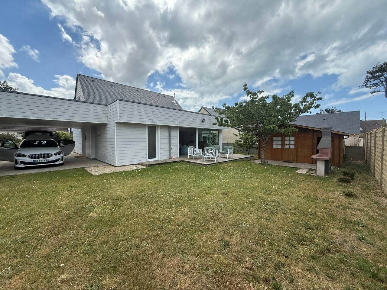 A residential property with a garage, a covered patio, and a lawn.