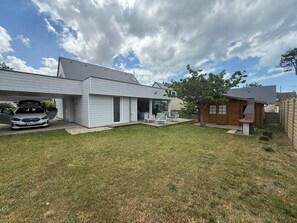 Ein Wohnhaus mit Garage, überdachter Terrasse und Rasenfläche.