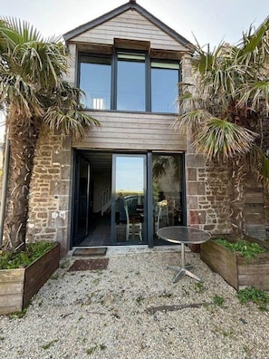 A modern two-story house with a stone facade, large glass doors, and a gravel driveway. - The Palm Trees of Regnèville (Regnéville-sur-Mer)