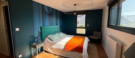 A bedroom with a bed, a nightstand, a window, and a radiator.